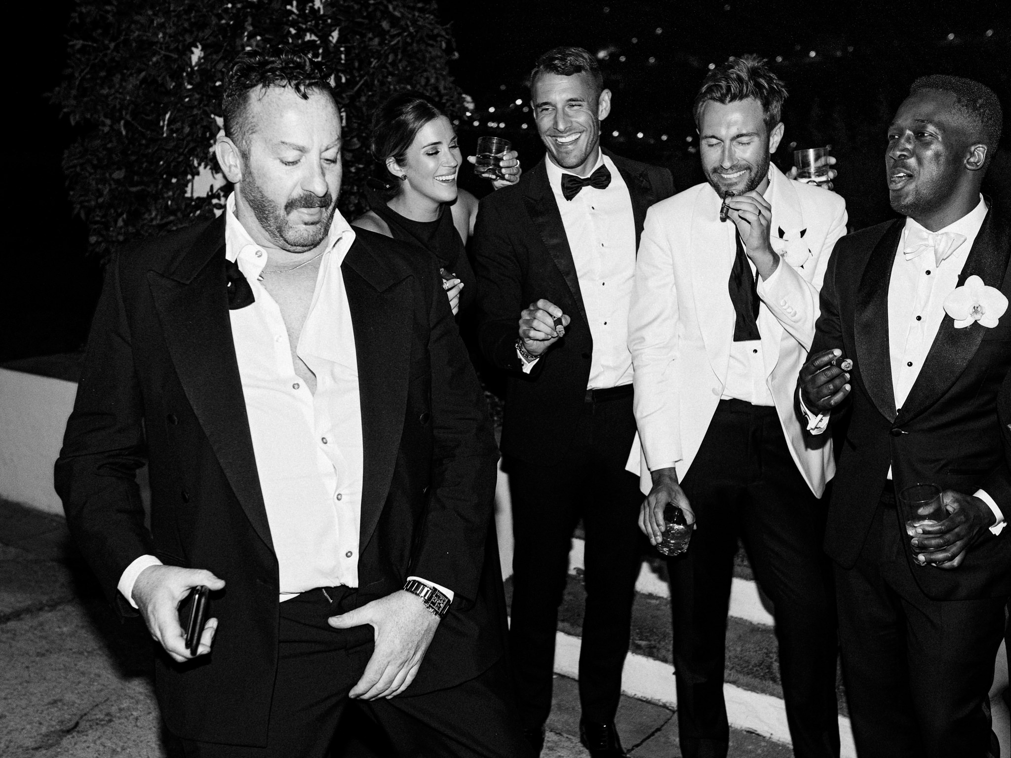 Guests in black tie laughing and dancing with cigars and drinks at the after-party